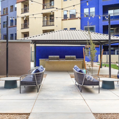 a patio with chairs and tables and a building with a blue roof